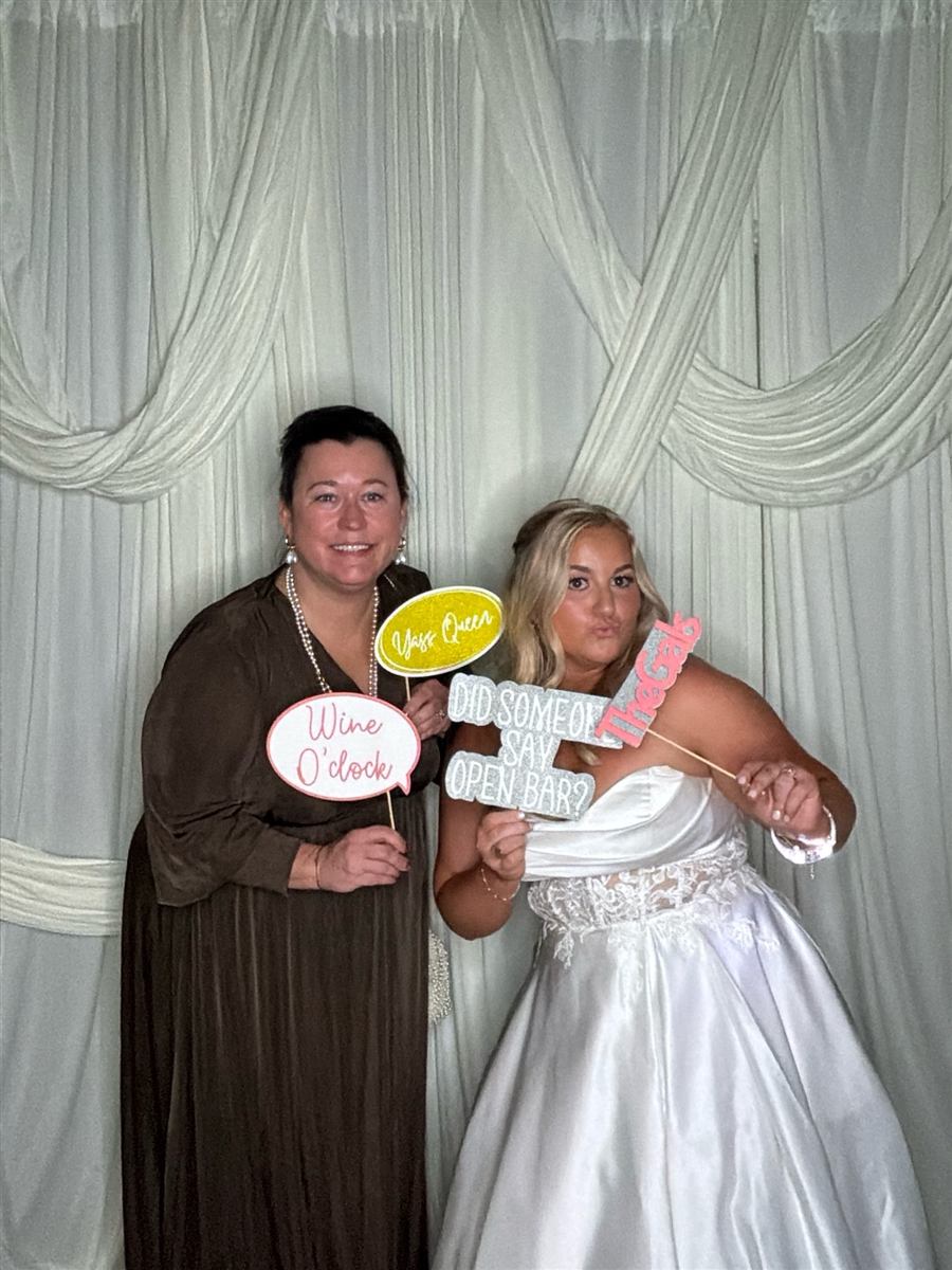 Bride posing with a prop sign in the photo booth