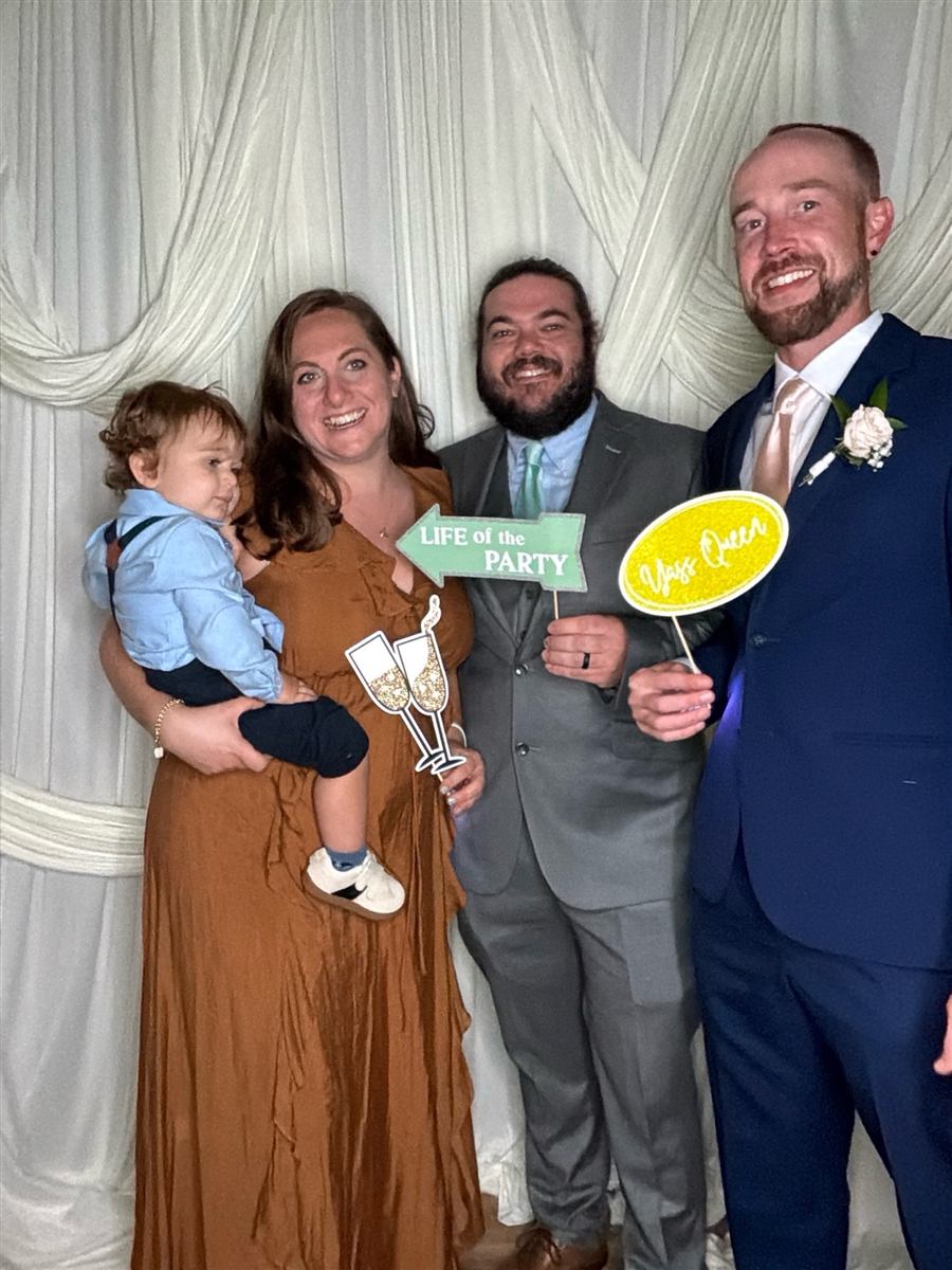 A family with a baby holding props in the photo booth